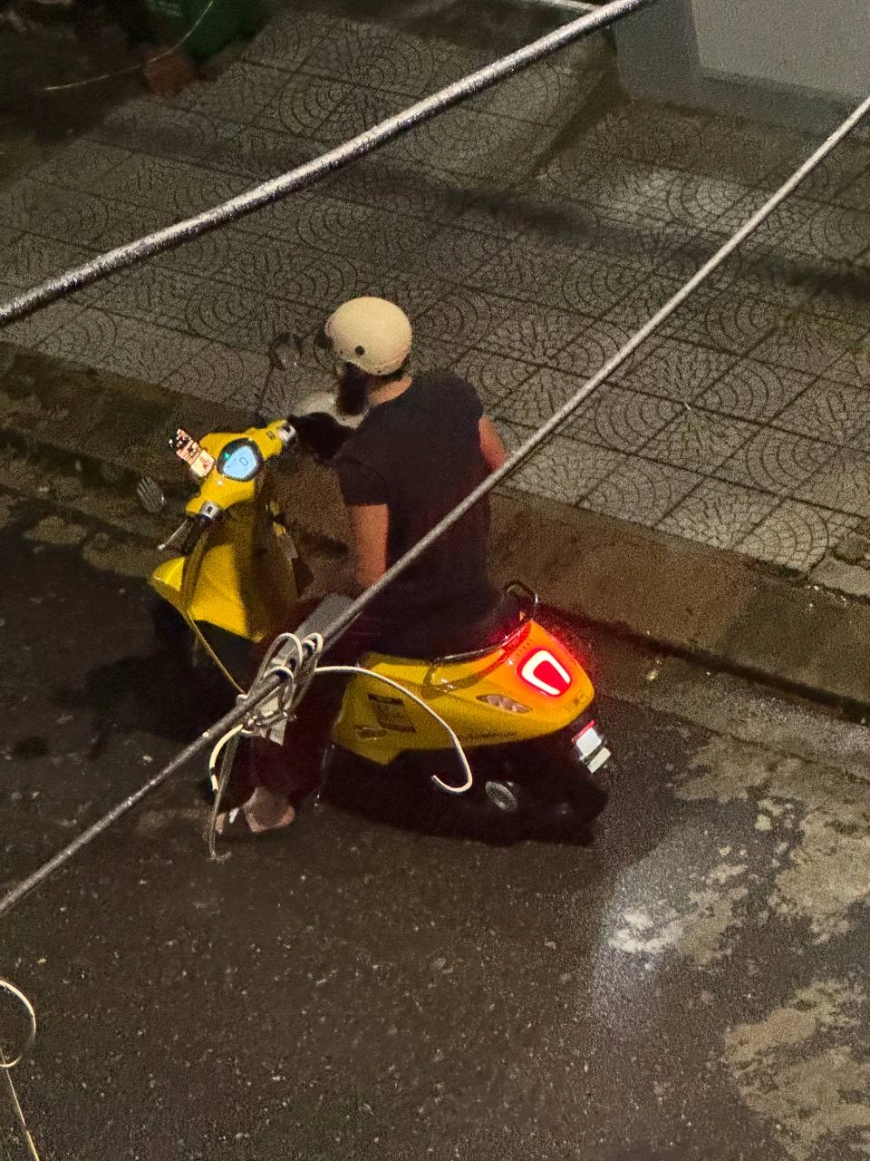 a hideous image of a man on a yellow ebike on a vietnamese city street