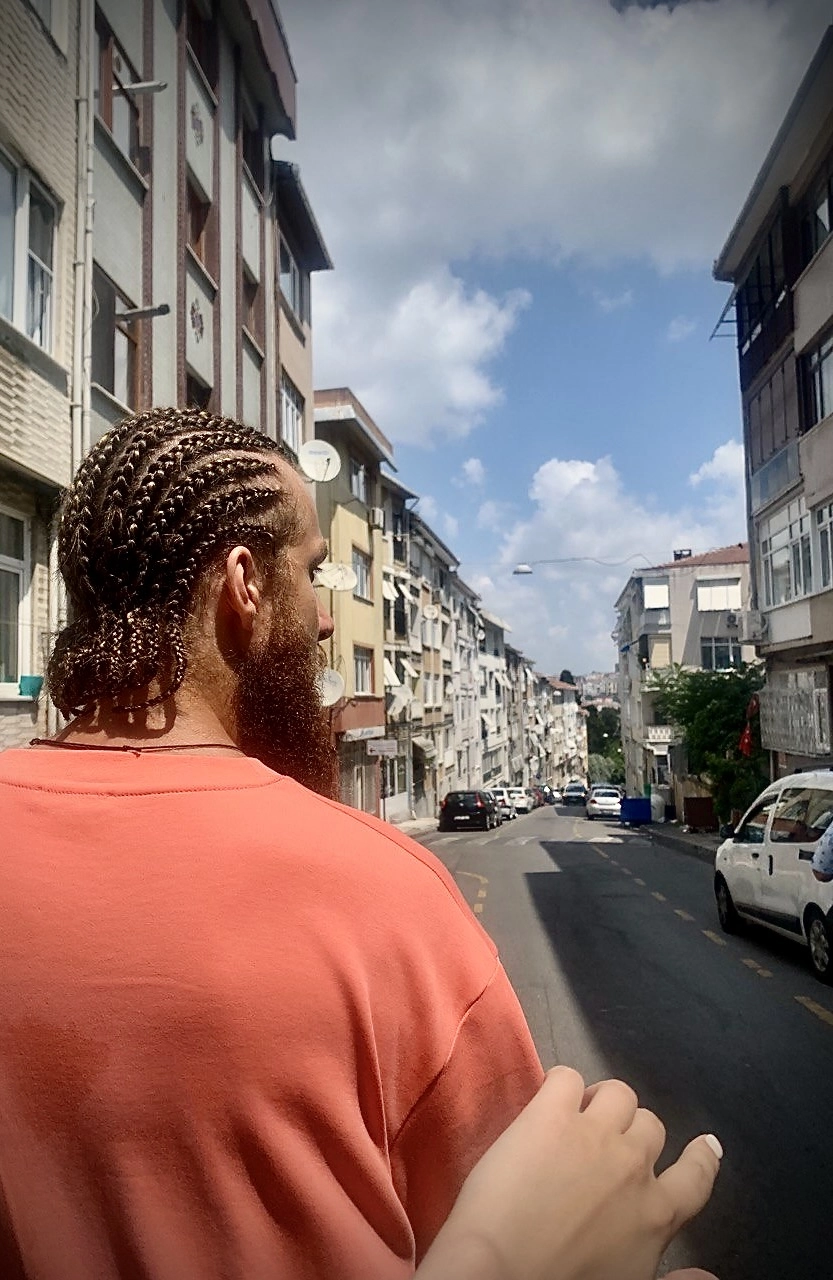 an outstretched female hand towards a man with cornrows and a pink shirt in Istanbul, Turkey